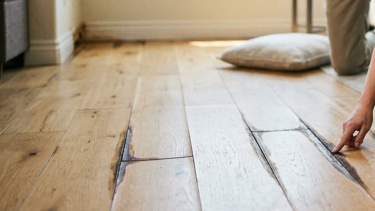 Dark seams between hardwood floorboards after a slow plumbing leak